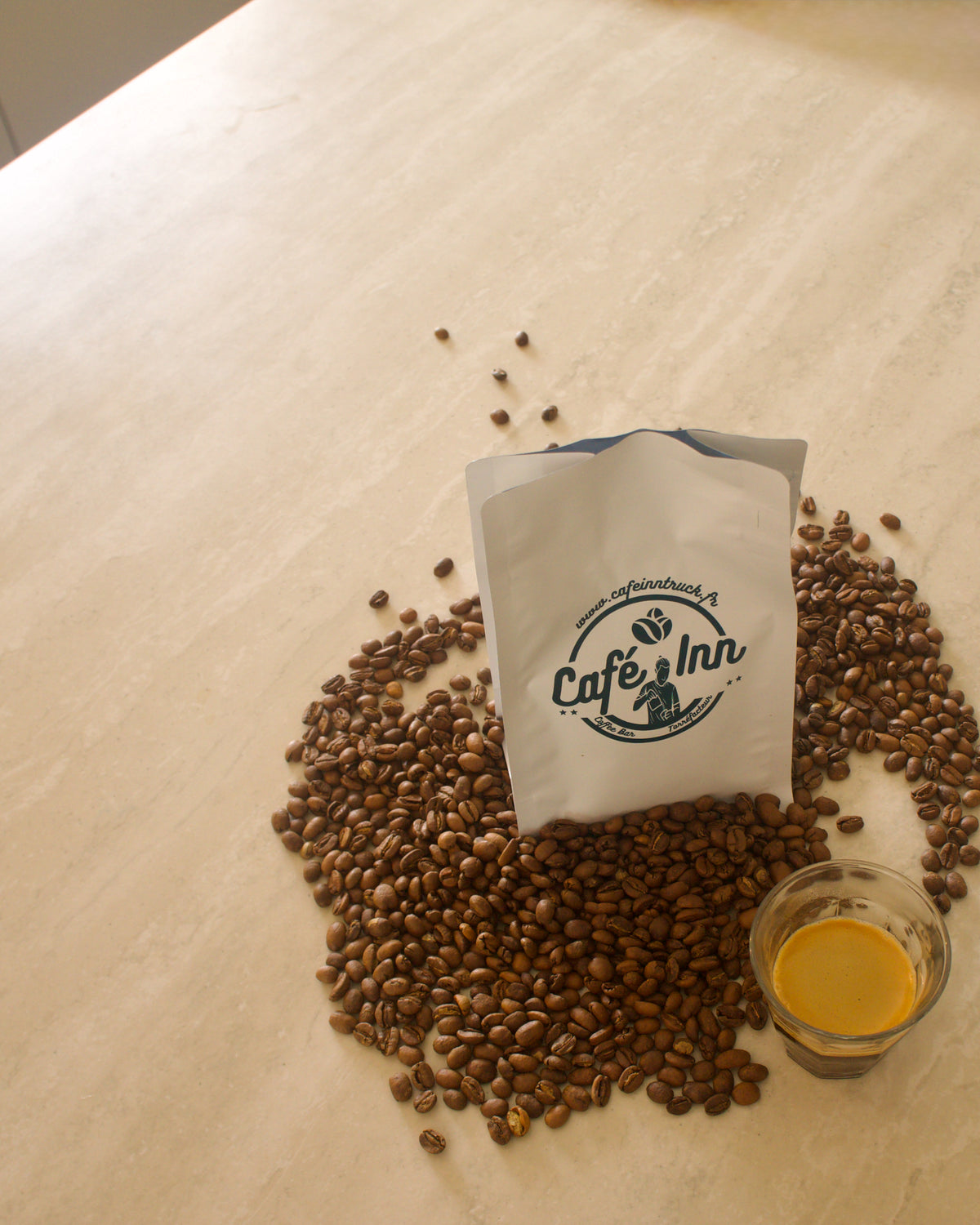 Sachet de café Café Inn entouré de grains de café et d’un espresso